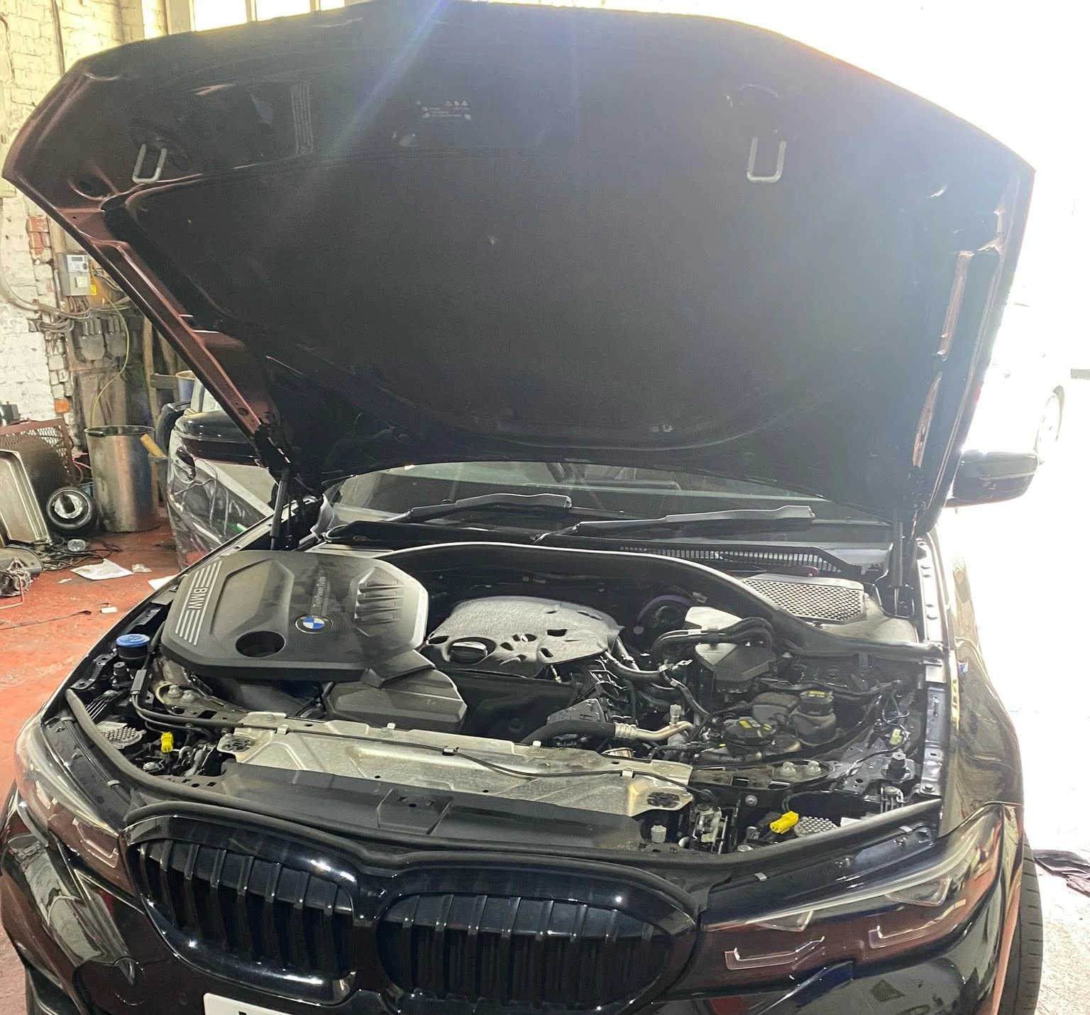 BMW with bonnet open in the workshop, registration concealed